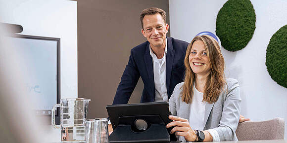 Zwei Mitarbeiter im Konferenzraum am Tisch vor einem LapTop